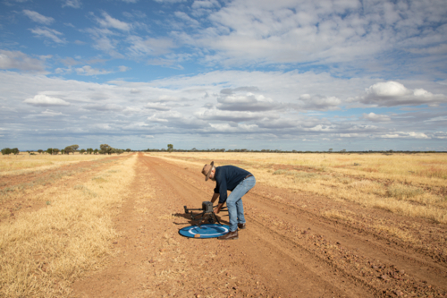 Man picking up agricultural drone from landing mat - Australian Stock Image