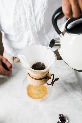 Man pouring boiling water from kettle into pour over coffee