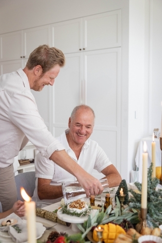 Man pouring water at Christmas table - Australian Stock Image