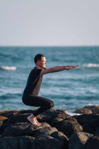 Man practising Yoga poses at the beach - Australian Stock Image