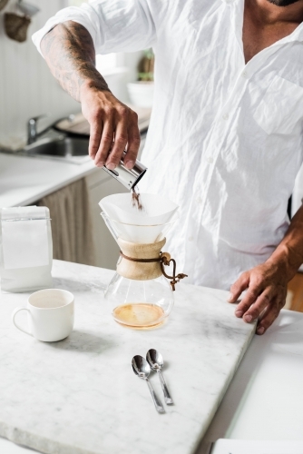 Man preparing a pour over coffee in his kitchen