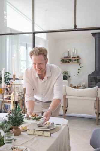 Man preparing table with Christmas decorations - Australian Stock Image
