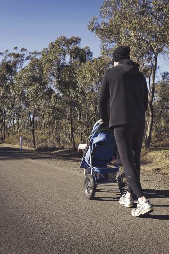 Man pushing a toddler in a stroller on a country road