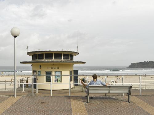 Man relaxing on Bondi Beach Promenade - Australian Stock Image