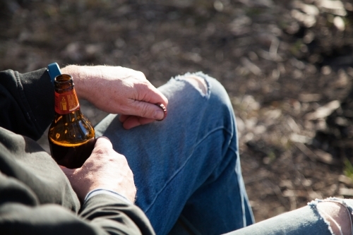 Man relaxing outside holding a bottle of beer