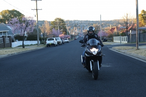 Man riding motorbike on a suburban street - Australian Stock Image