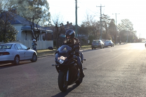 Man riding motorbike on a suburban street - Australian Stock Image