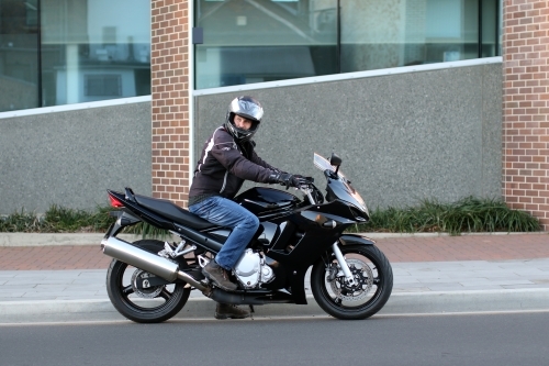 Man riding motorbike on a suburban street - Australian Stock Image