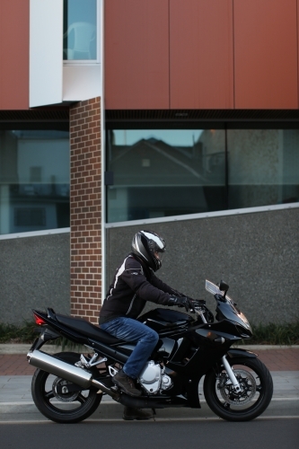 Man riding motorbike on a suburban street - Australian Stock Image