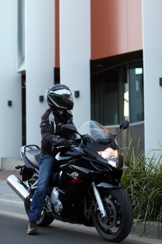 Man riding motorbike on a suburban street - Australian Stock Image