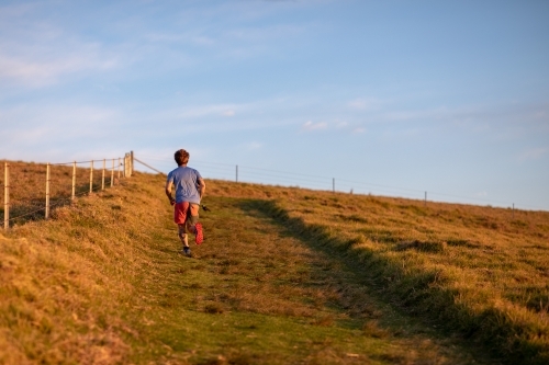 Man Running Uphill Alone on Paddock - Australian Stock Image