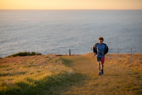 Man Running Uphill Away from Ocean - Australian Stock Image