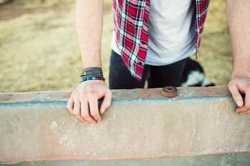 man's hands leaning on a steel barrier on a farm - Australian Stock Image