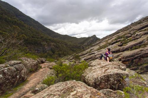 Man sitting alone in a large valley with overcast sky - Australian Stock Image