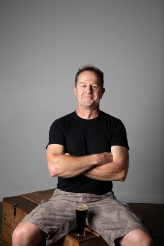 Man sitting, arms folded, relaxed and happy