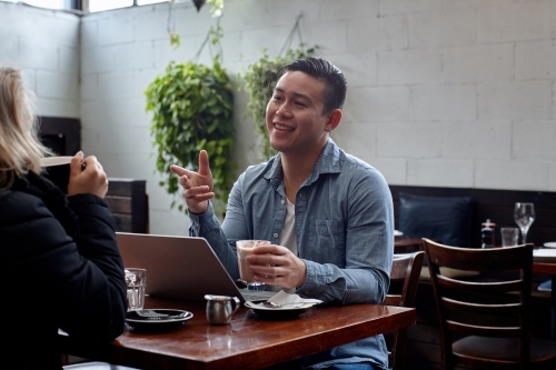 Man sitting at table at restaurant talking with friend