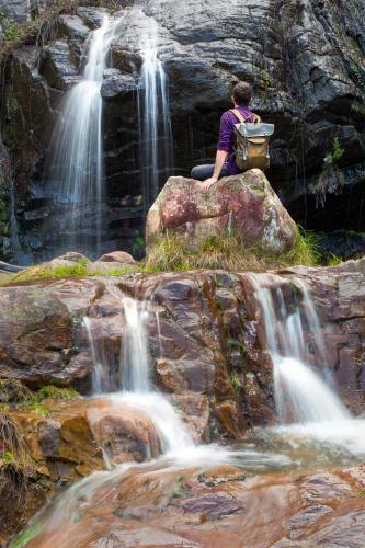 Man sitting by cascading waterfall