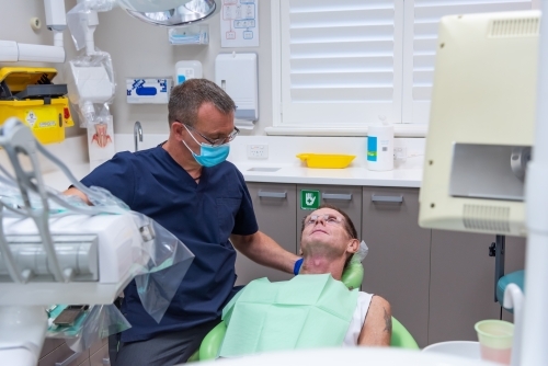 Man sitting in dental chair at dentist - Australian Stock Image