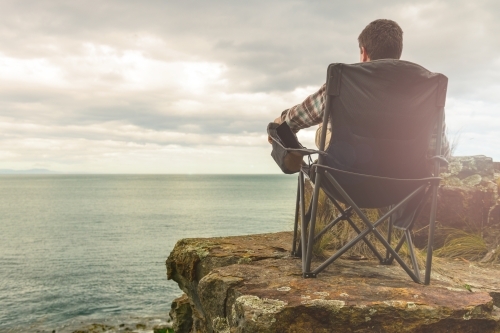 man sitting in tranquil camp spot by the ocean in his chair