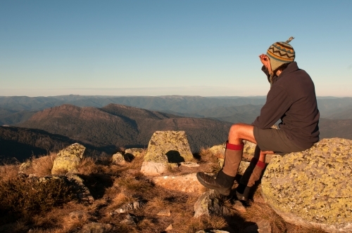 Man sitting on a rock looking out over mountain range