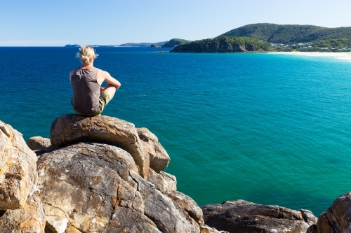 Man sitting on a rocky headland looking out to sea