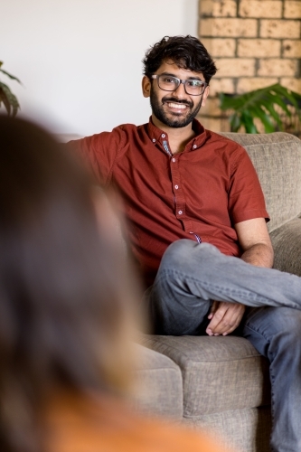 man sitting on couch talking with his partner