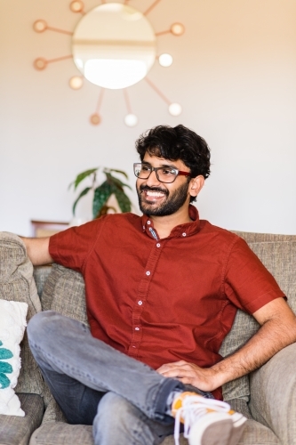 man sitting on sofa at home - Australian Stock Image
