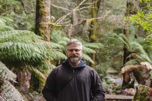 Man standing, facing the camera in bushland - Australian Stock Image