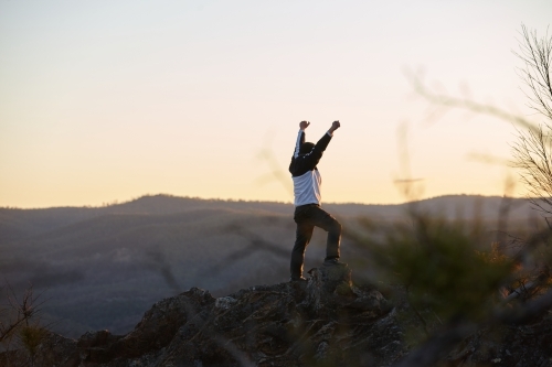Man standing looking out over mountains on sunset - Australian Stock Image