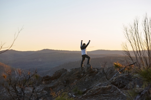 Man standing looking out over mountains on sunset - Australian Stock Image