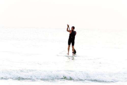 Man standing on paddleboard looking out to sea in very high light - Australian Stock Image