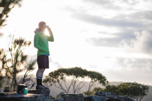 Man standing on rocks drinking tea - Australian Stock Image
