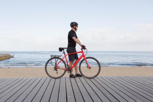 Man standing with bike looking at view of a Melbourne beach - Australian Stock Image