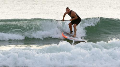 Man steering  paddleboard through wave