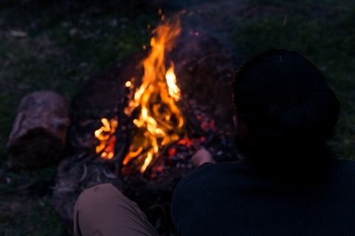 Man stoking roaring camp fire at night