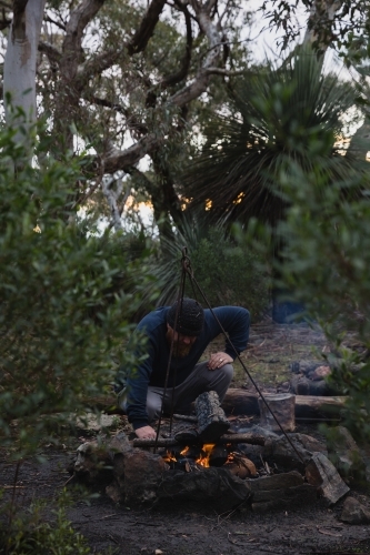 Man tending to camp fire - Australian Stock Image