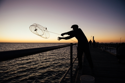 Man throwing crab pot at sunset