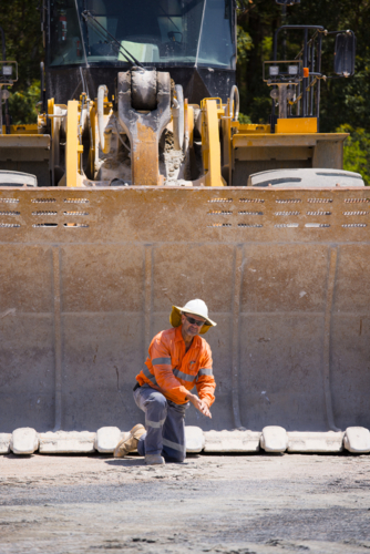 Man tightening the bolts on the bucket of a payloader. - Australian Stock Image