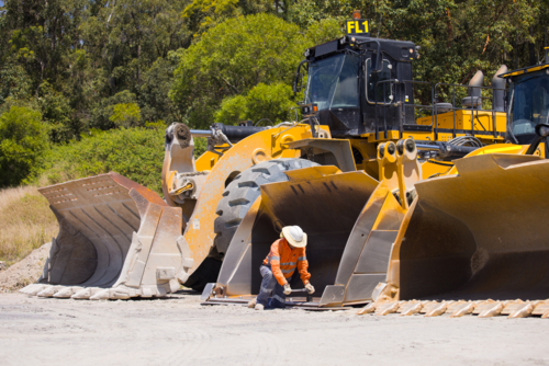 Man tightening the bolts on the bucket of a payloader. - Australian Stock Image