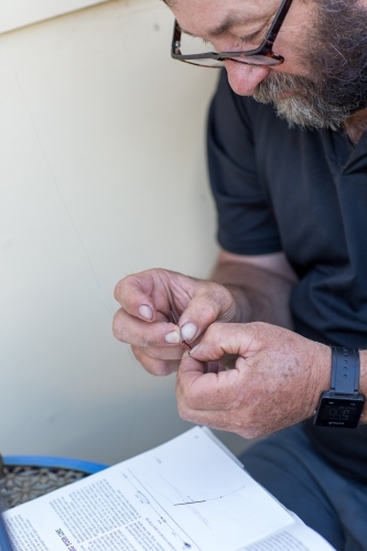 Man trying to thread fishing line through hook