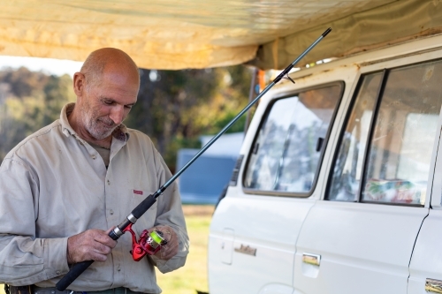 man under awning with fishing rod - Australian Stock Image