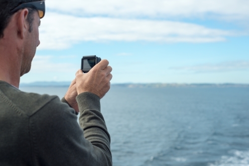 Man using GoPro video camera on boat