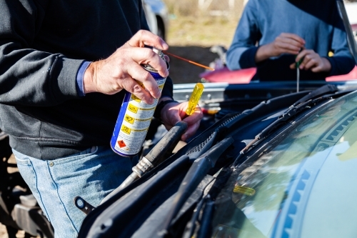 Man using grease to pull apart smashed car for parts - Australian Stock Image