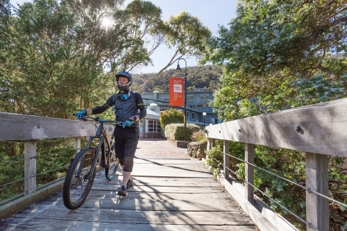 Man walking his mountain bike to the ski lift in summer at Thredbo - Australian Stock Image