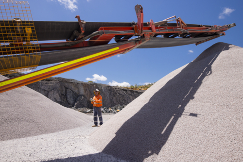 Man walking in between piles of aggregates near the crusher. - Australian Stock Image