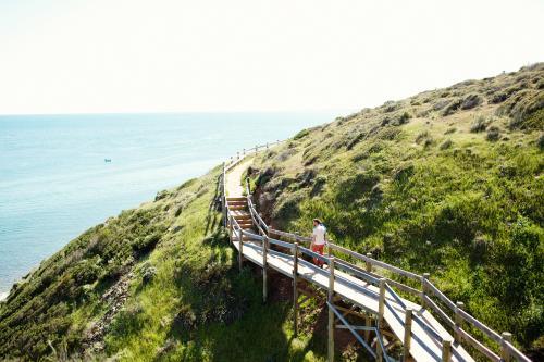 Man walking on a walkway over a mountain on the coast - Australian Stock Image