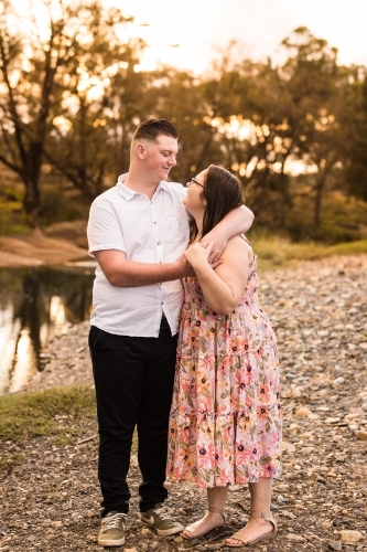 Man with arms around girlfriends shoulders looking at each other in love - Australian Stock Image