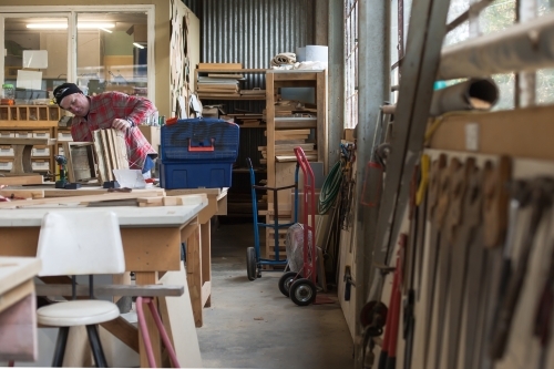 Man working at a Men's shed with tools on the wall - Australian Stock Image