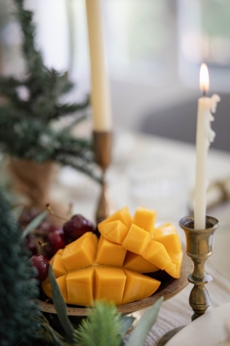 Mango and cherries in bowl on decorated Christmas table - Australian Stock Image