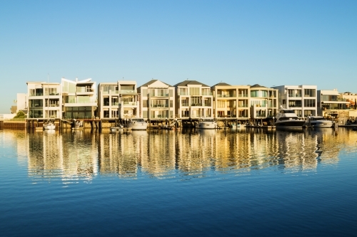 Marina homes reflecting in the water in morning light - Australian Stock Image